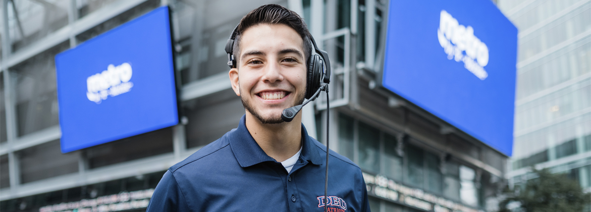 Man smiling in front of the stadium, wearing an DBU t shirt