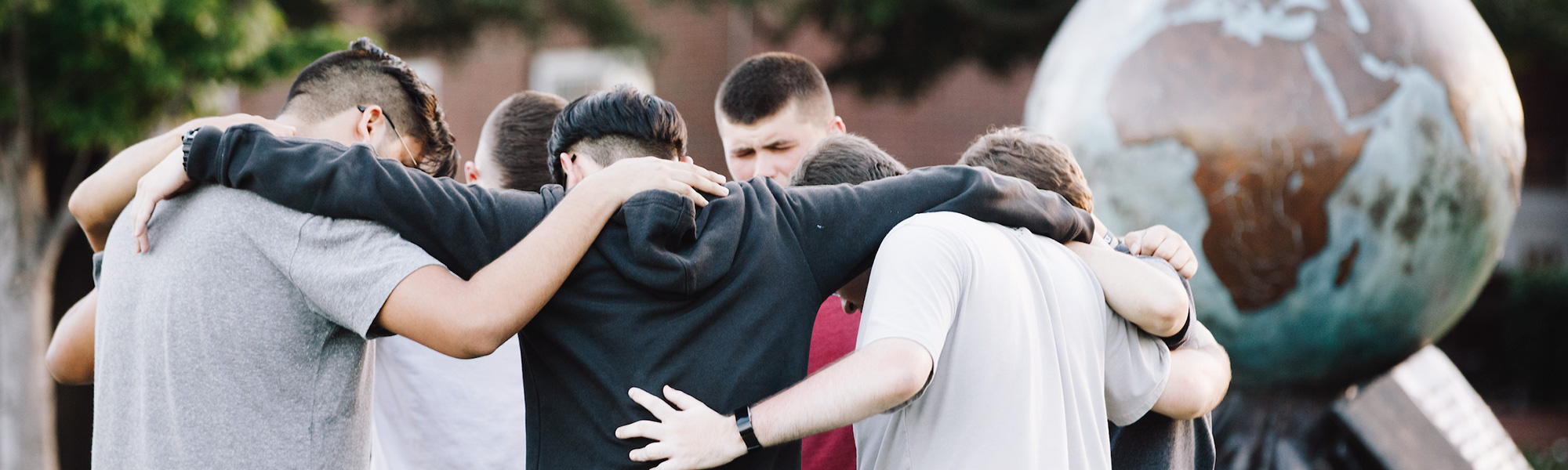 boys pray in front of a globe