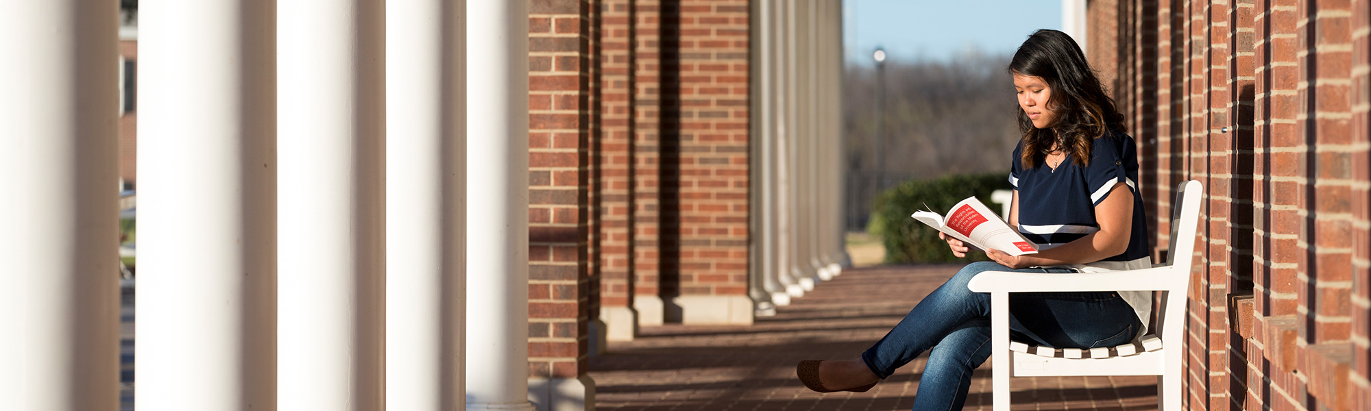 girl sits on bench reading