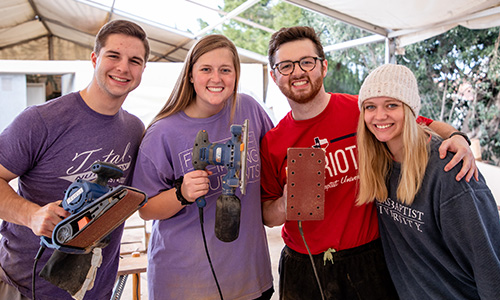 Students smile while holding belt grinders