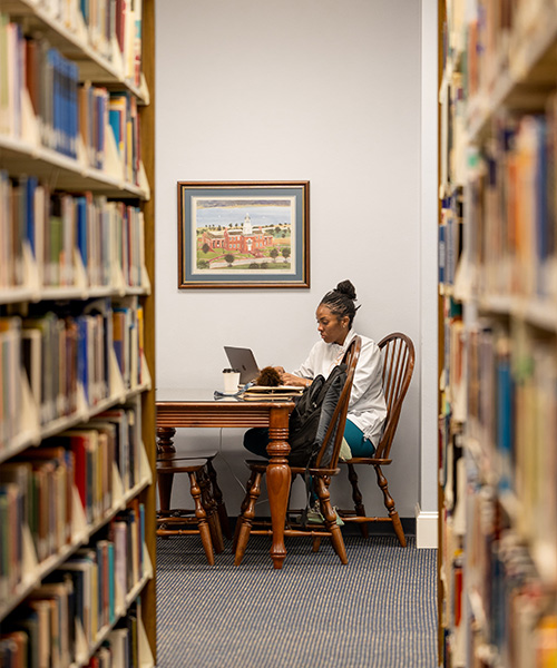 college student sitting at table in library