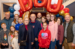group of people standing by stairs with balloons spelling out DBU