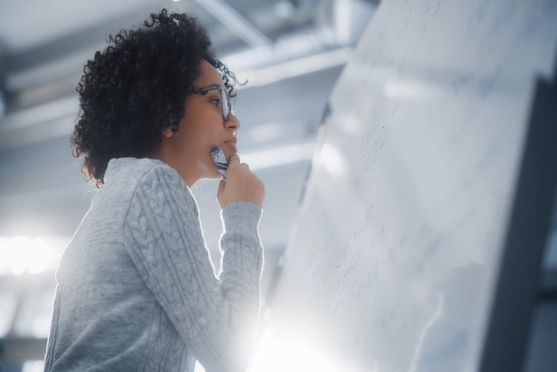 female engineer wearing glasses looking at a board working on an important engineering project