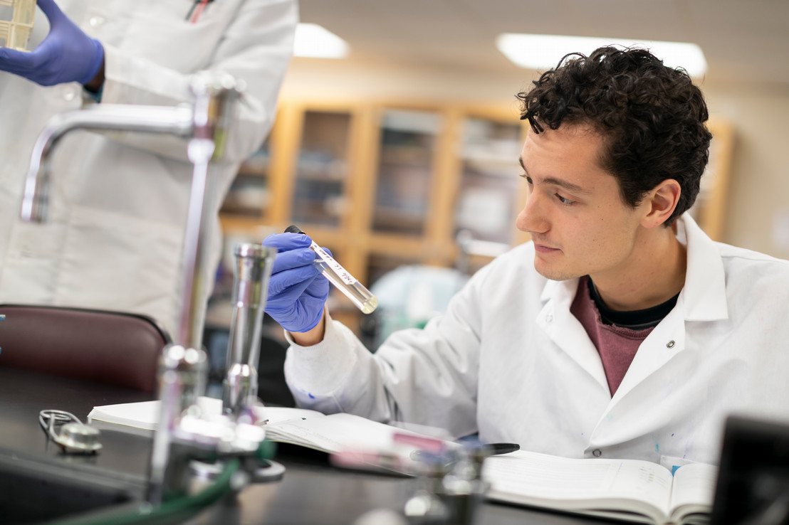 college student in lab coat holding vile in science lab in Dallas, TX