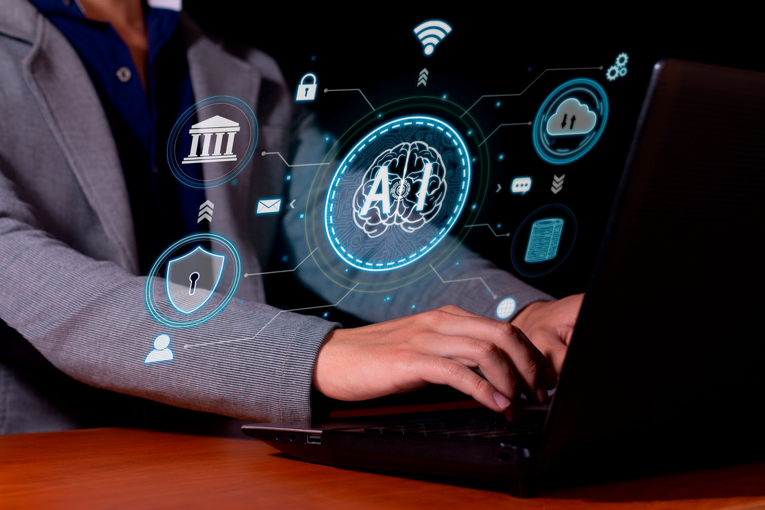 Dallas, Texas - Man typing on a laptop keyboard with imaginative floating AI symbol graphic overlay