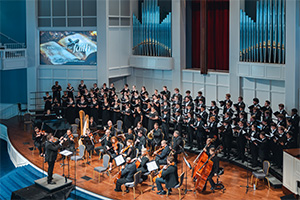 A choir and orchestra performing in a grand auditorium