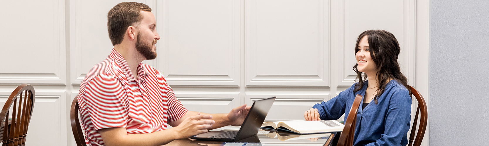 two graduate students talking while they study in the library