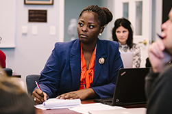 woman looking up as she takes notes in class