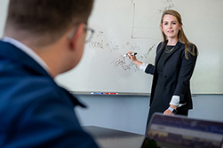 professor standing by whiteboard teaching a student