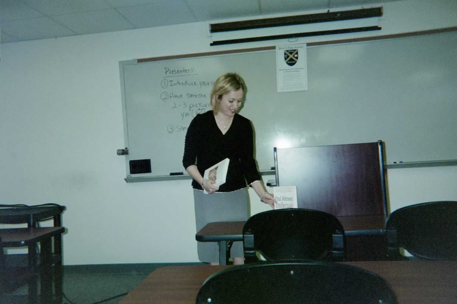 picture of a woman setting book down on the desk in front of the podium