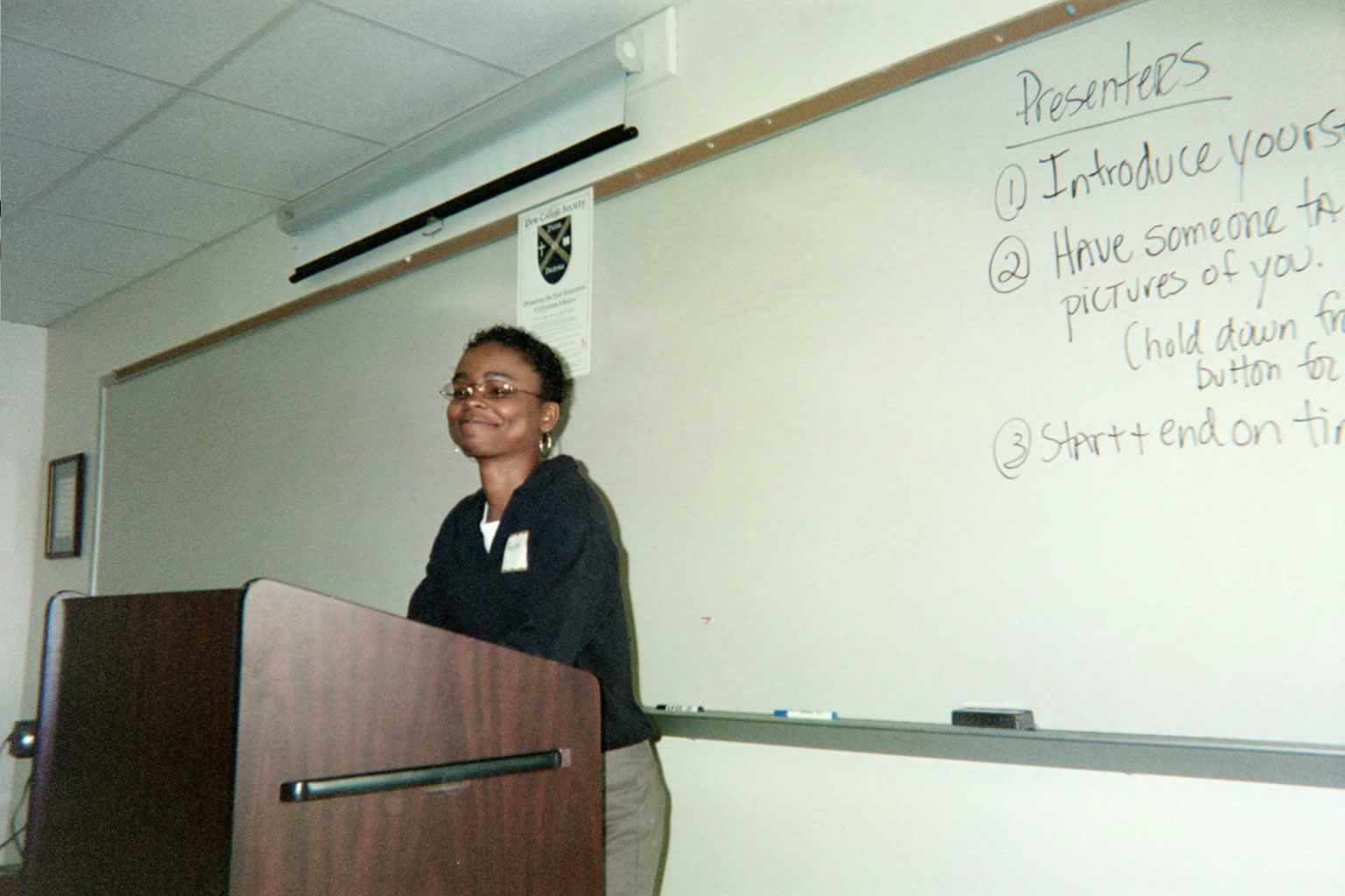 picture of a woman standing behind a podium smiling