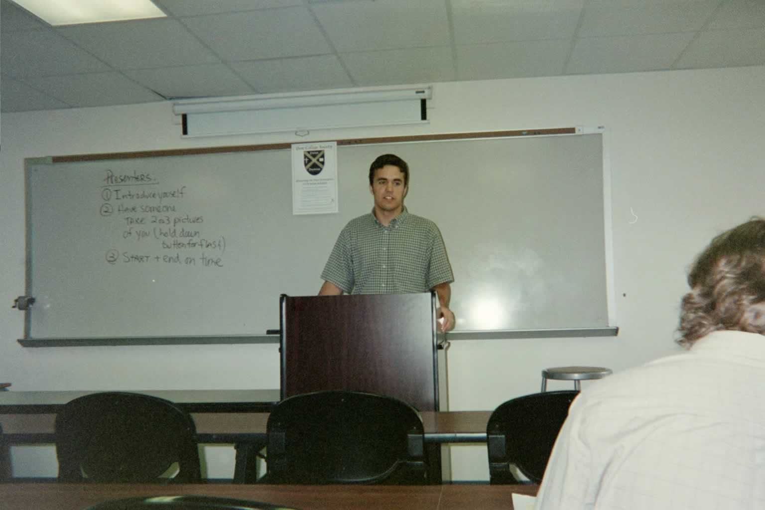 picture of a man standing and talking behind a podium in a classroom