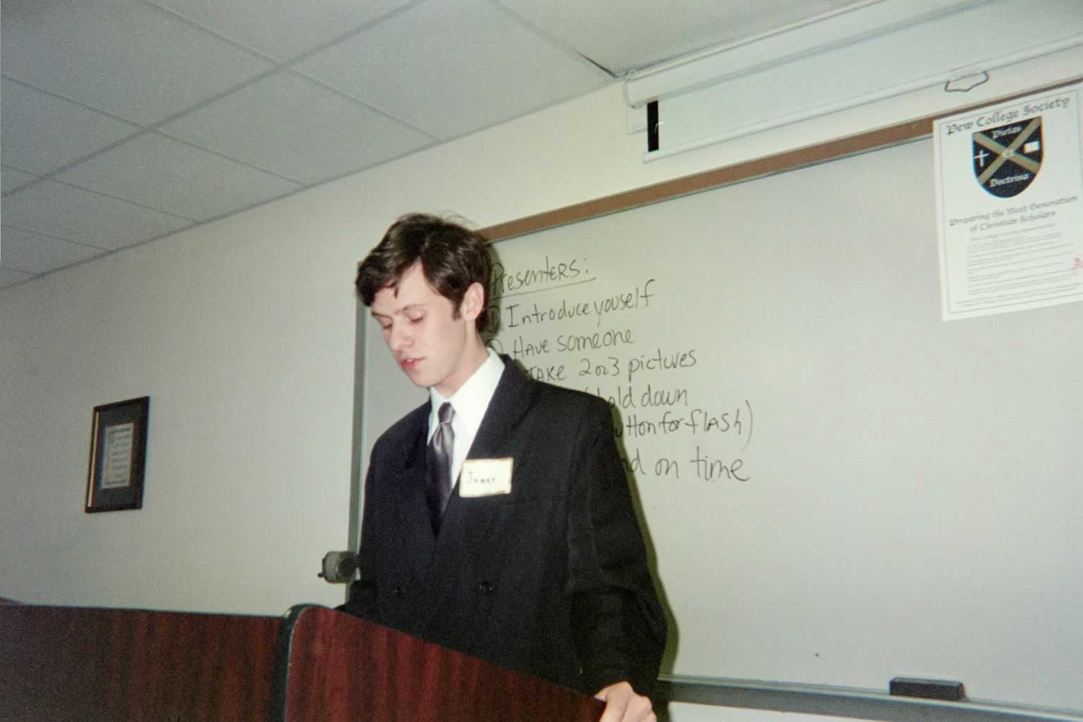 picture of a man in a suit standing behind a podium speaking