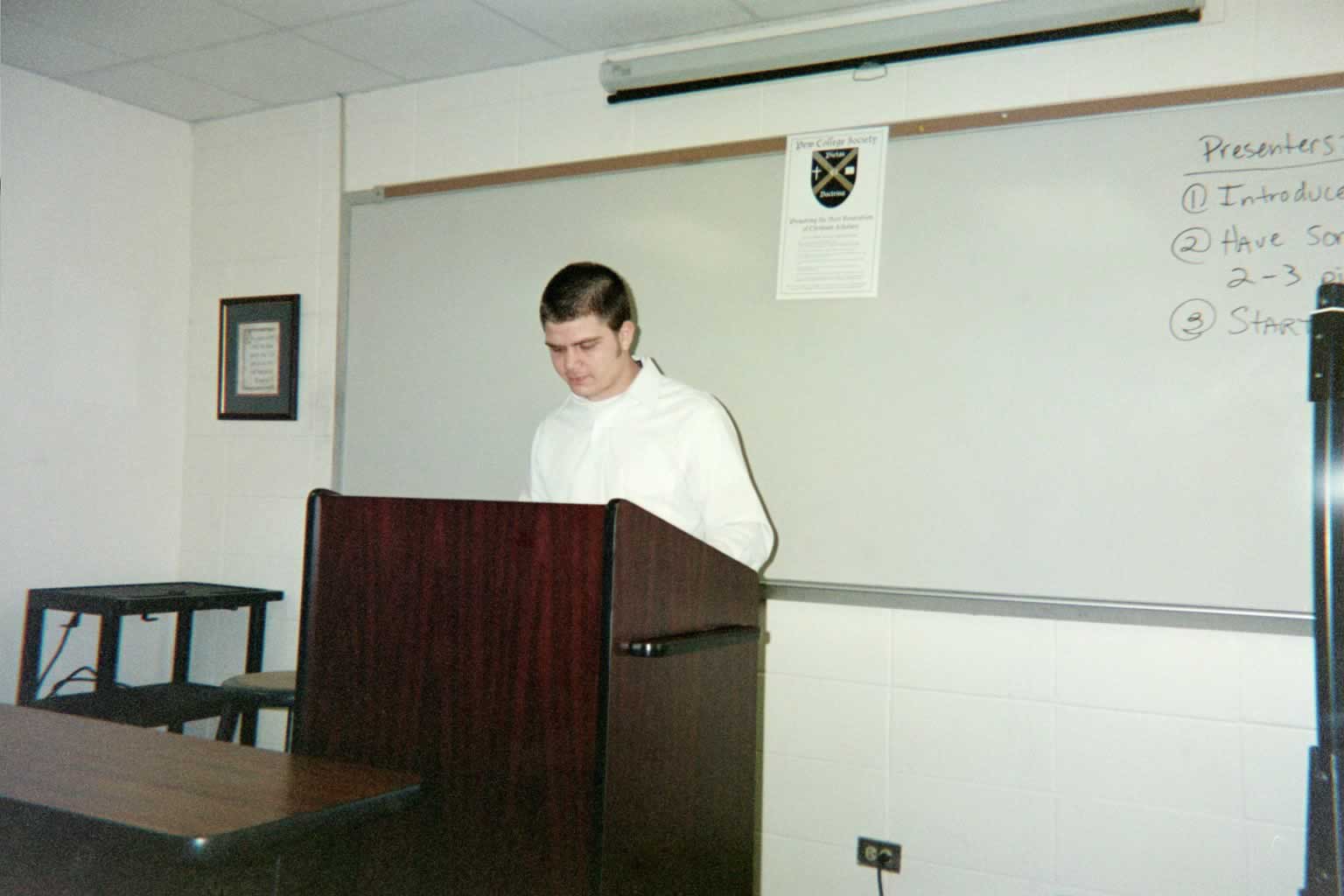 picture of a man in a white shirt standing behind a podium