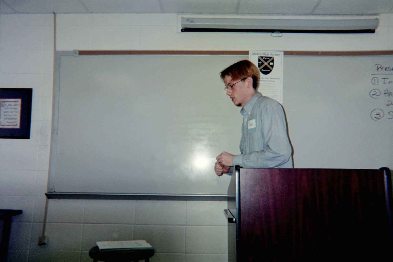 picture of a man in a blue shirt with glasses walking away from the podium