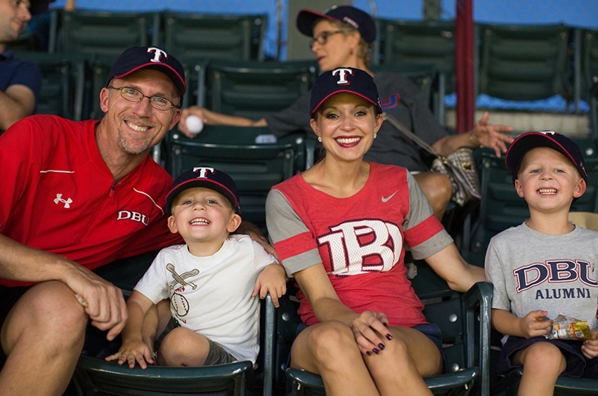 Dr. Gandy, Professor of Management, smiles alongside his wife and two sons at the ball game