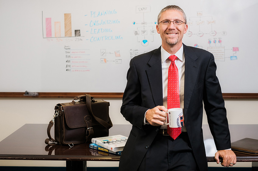 Dr. Justin Gandy in front of a whiteboard displaying management tactics