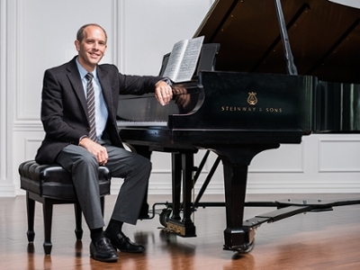 Dr. Wes Moore sits in front of a Steinway piano on the chapel stage