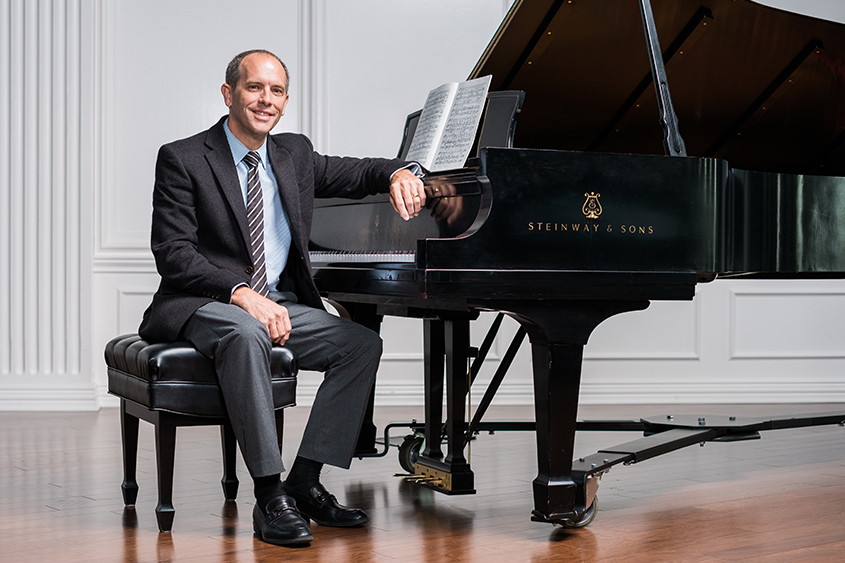 Dr. Wes Moore sits in front of a Steinway piano on the chapel stage