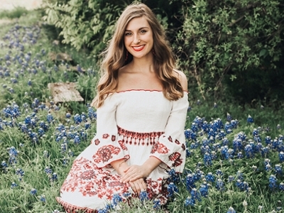 Allie sits in a field of bluebonnets