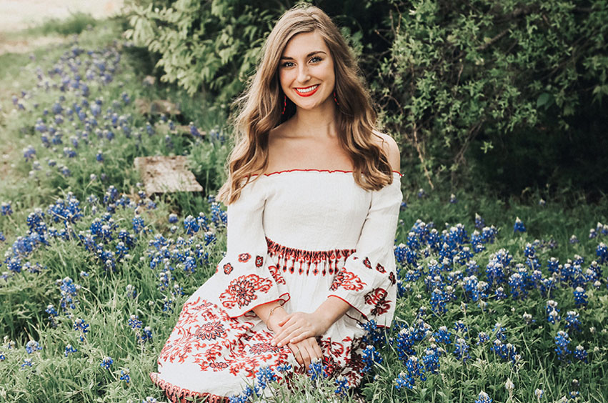 Allie sits in a field of bluebonnets