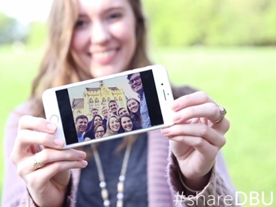 Sarah Edwards, a staff member, holds up a photo of her favorite memory from a travel study with DBU