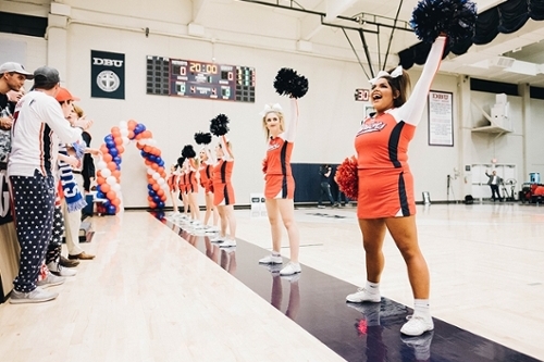 A line of DBU cheerleaders on the basketball court cheering on the blue line