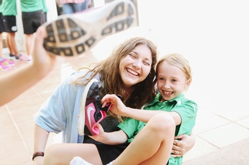 Two girls posing together, one has her eyes closed and is brunette and the other is a girl with a green shirt