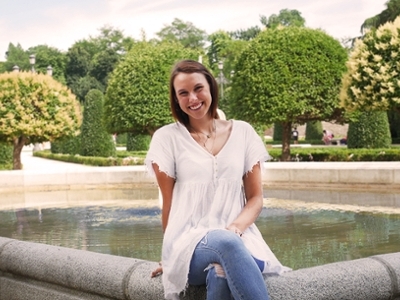 Corinna sits on a fountain in a Spanish garden