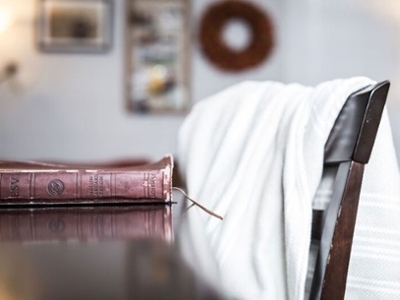 A Bible rests on the dining table with the sunrise peeking through the window