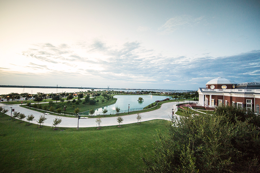 Overlooking campus from the Chapel balcony with Nation Hall and Swan Lake lit by the sunset on the horizon