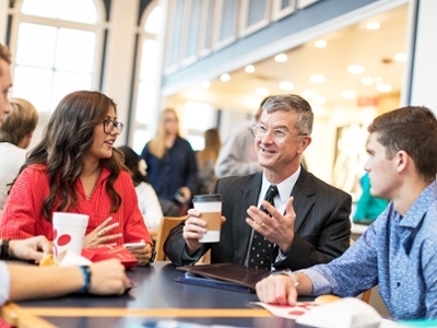 Dr. Ross O'Brien fellowships with students at a table at Chick-fil-a on campus