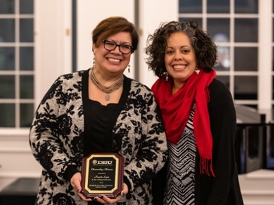 Two ladies standing together holding a plaque. 