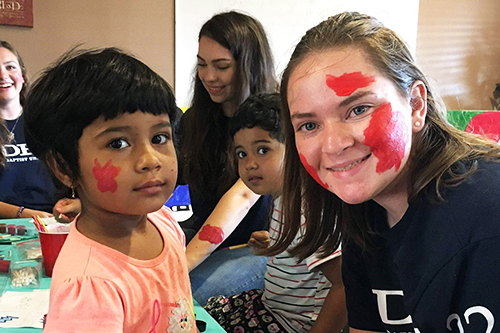 A female DBU student is smiling with a little girl. 