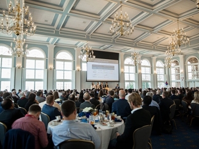 Guests at the Lion's U event are sitting at tables listening to a presentation. 