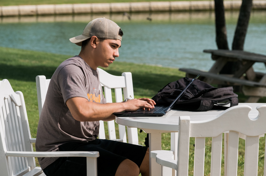 college guy working on college coursework outside near pond in Dallas, Texas