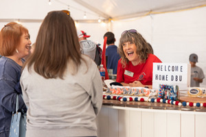 alumni talking in the alumni tent at homecoming