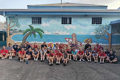 DBU volleyball and soccer volunteers smiling in group photo outside