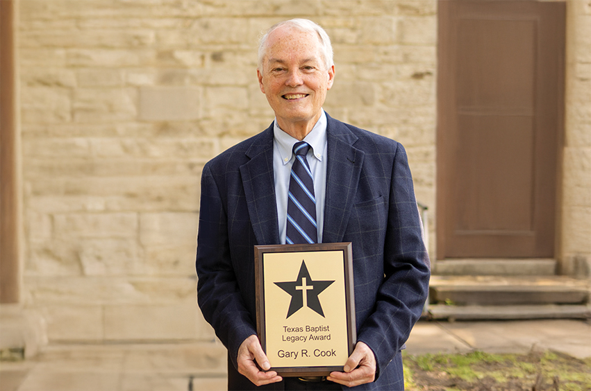 Dr. Cook standing outside holding his Texas Baptist Legacy Award