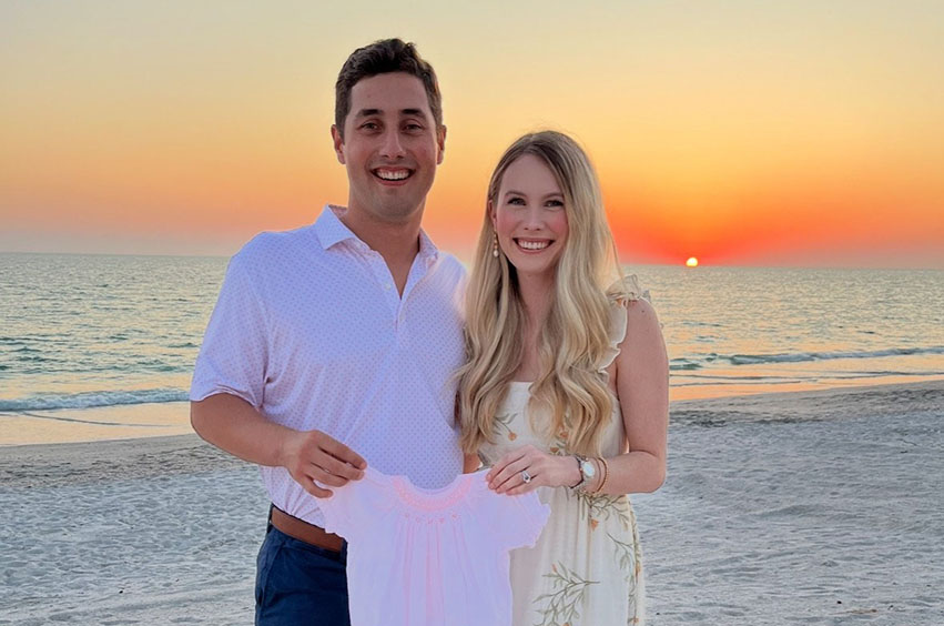 John Austin Earles standing outside with his wife with sunset in the background above the water