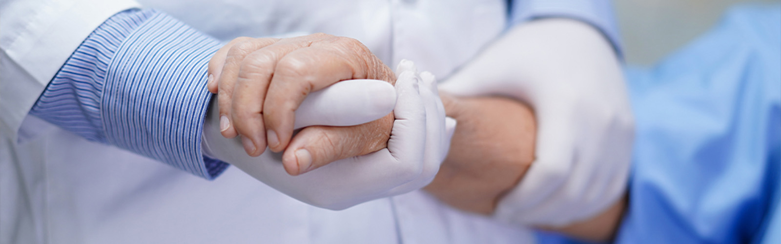 gloved hand holding hands with the patients hand