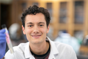 student smiling while holding test tube 