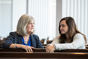 professor and student talking in the chapel while sitting