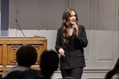 picture of a woman in a business suit speaking at a podium in front of people