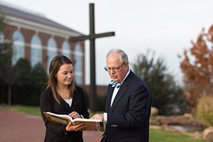 professor talking with student infront of the cross outside 