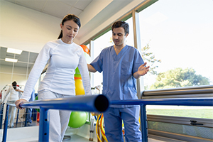 man in blue scrubs assisting a women with her therapy