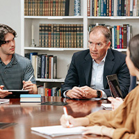 students seated around a large table while listing quietly to a professor